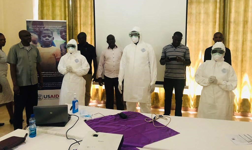 A group of trainees stand, some wearing personal protective equipment, during the training