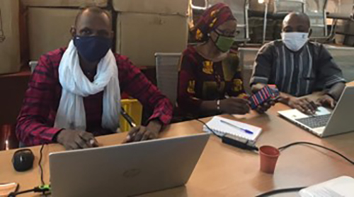 Three people sitting around a table looking at computers